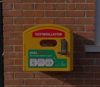 Automated external defibrillator a yellow box located on the eastern exterior brick wall of Petersfield Museum and Art Gallery.