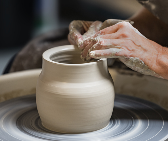 A person's hands making a clay pot

Description automatically generated