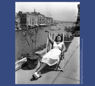 Peggy Guggenheim sitting in a deck chair on a patio facing the Grand Canal