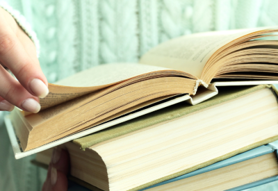 Woman holding books and flipping through pages.