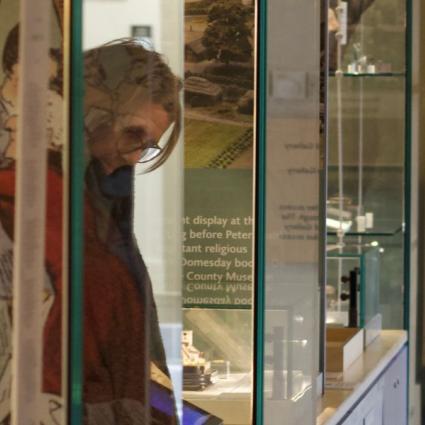 Loan woman in front of glass case