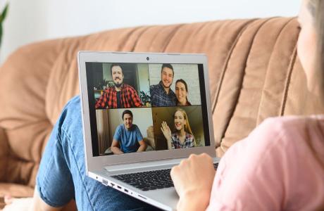 Woman on sofa watchin a zoom call on laptop