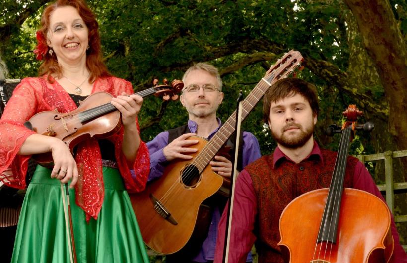 Woman with violin, man with guitar, and man with cello smiling at the camera