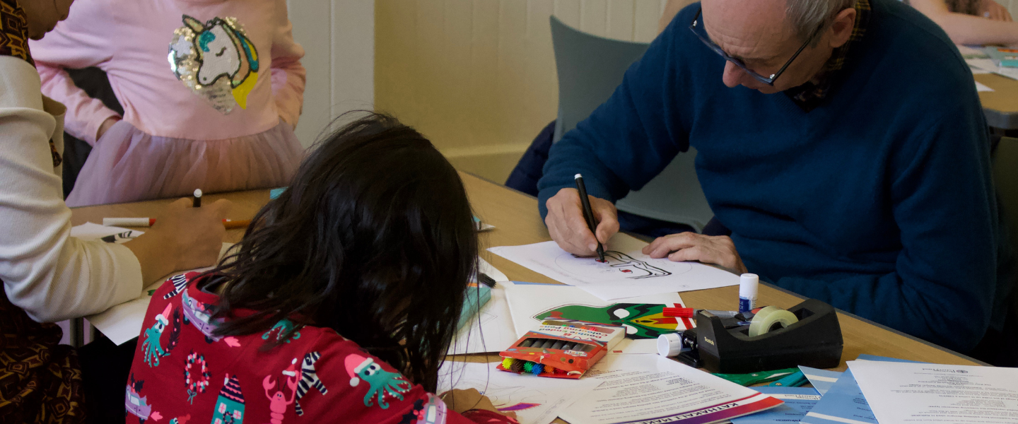 Family crafting together on a table in the Courthouse of Petersfield Museum and Art Gallery.