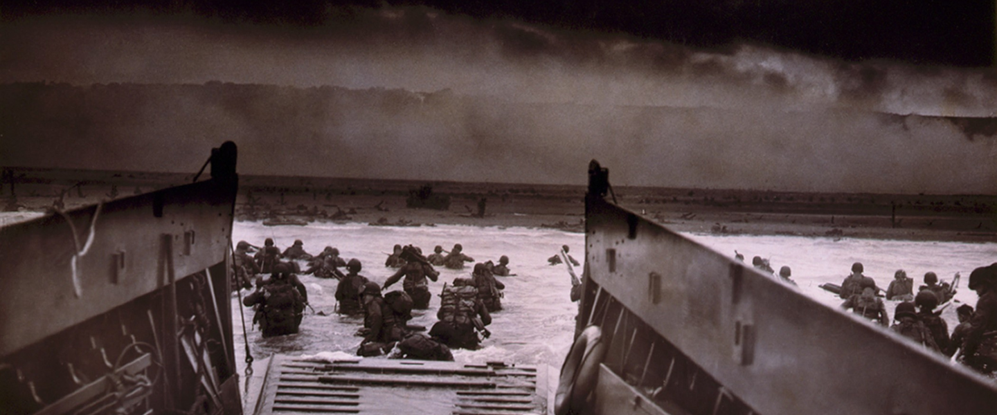 D Day scene from the boat of troops in the water walking to land.