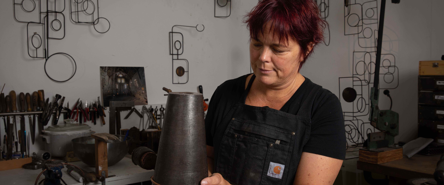 Artist Jacky Oliver in her studio surrounded by metal and wire art