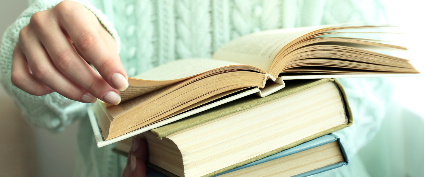 Woman holding books and flipping through pages.