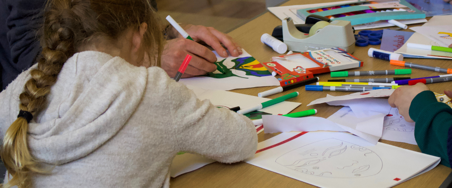 Kids and families crafting and colouring masks for creative workshop.