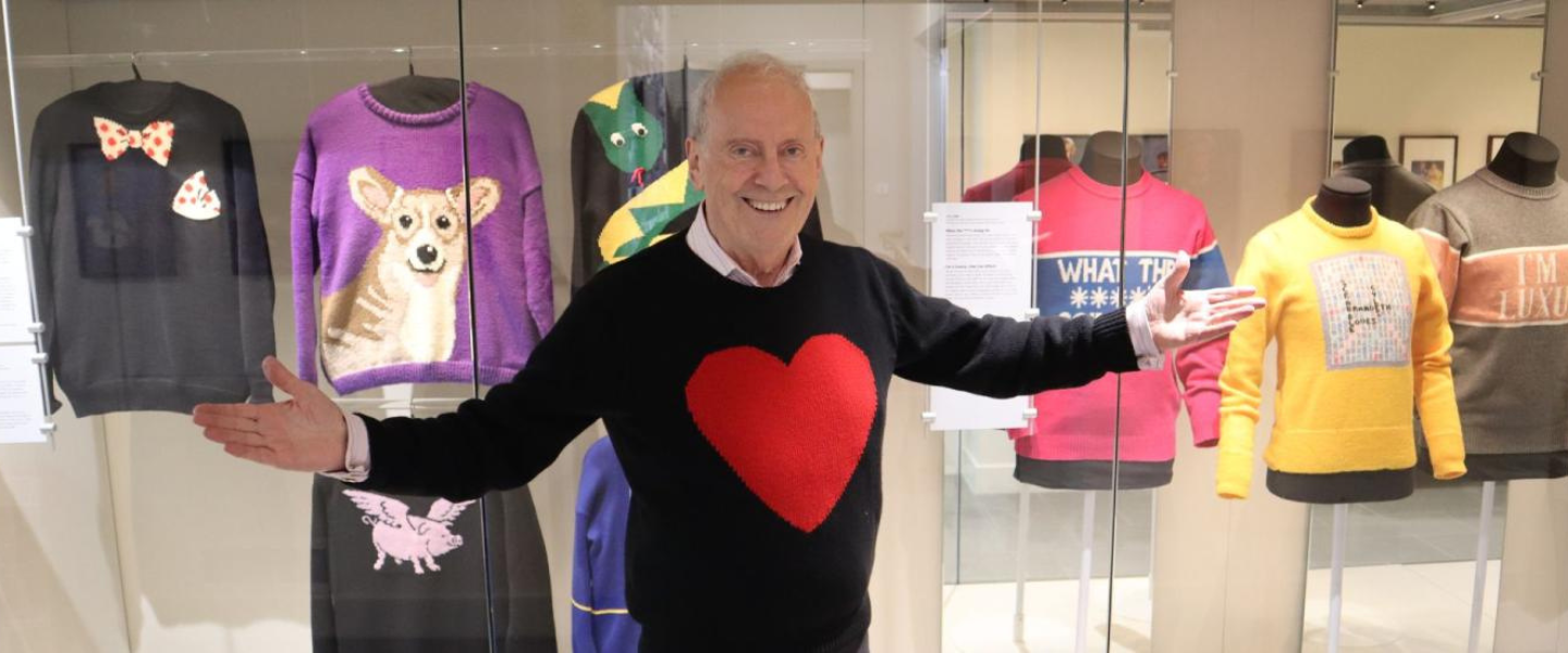 Gyles Brandreth standing in front of his jumpers on display